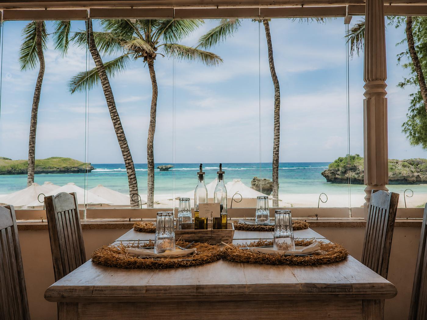 A table set for lunch with the lagoon and palms beyond the window